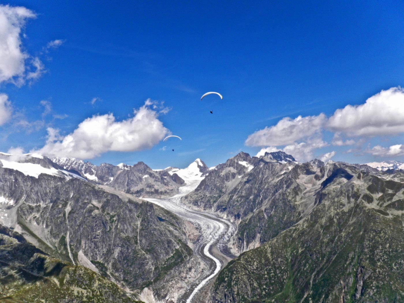 alpenflug-gleitschirm Diese zwei Gleitschirme haben die erste Talquerung schon fast geschafft. Auf der anderen Seite geht es wieder hoch.
