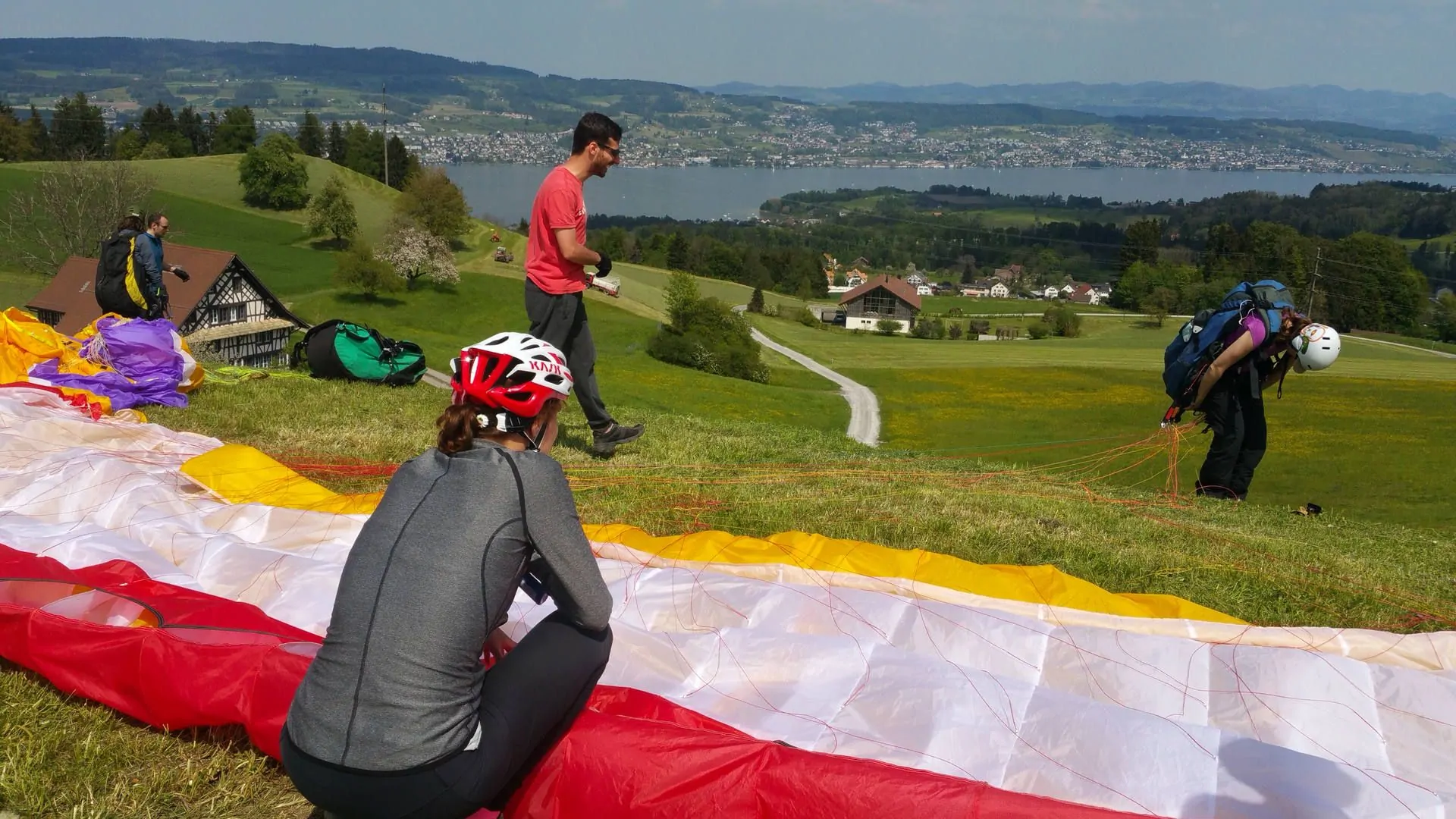 gleitschirm-schnuppertag-startvorbereitung-teilnehmer-quer Teilnehmer beim Gleitschirm-Schnuppertag helfen sich bei den Startvorbereitungen gegenseitig beim Auslegen.