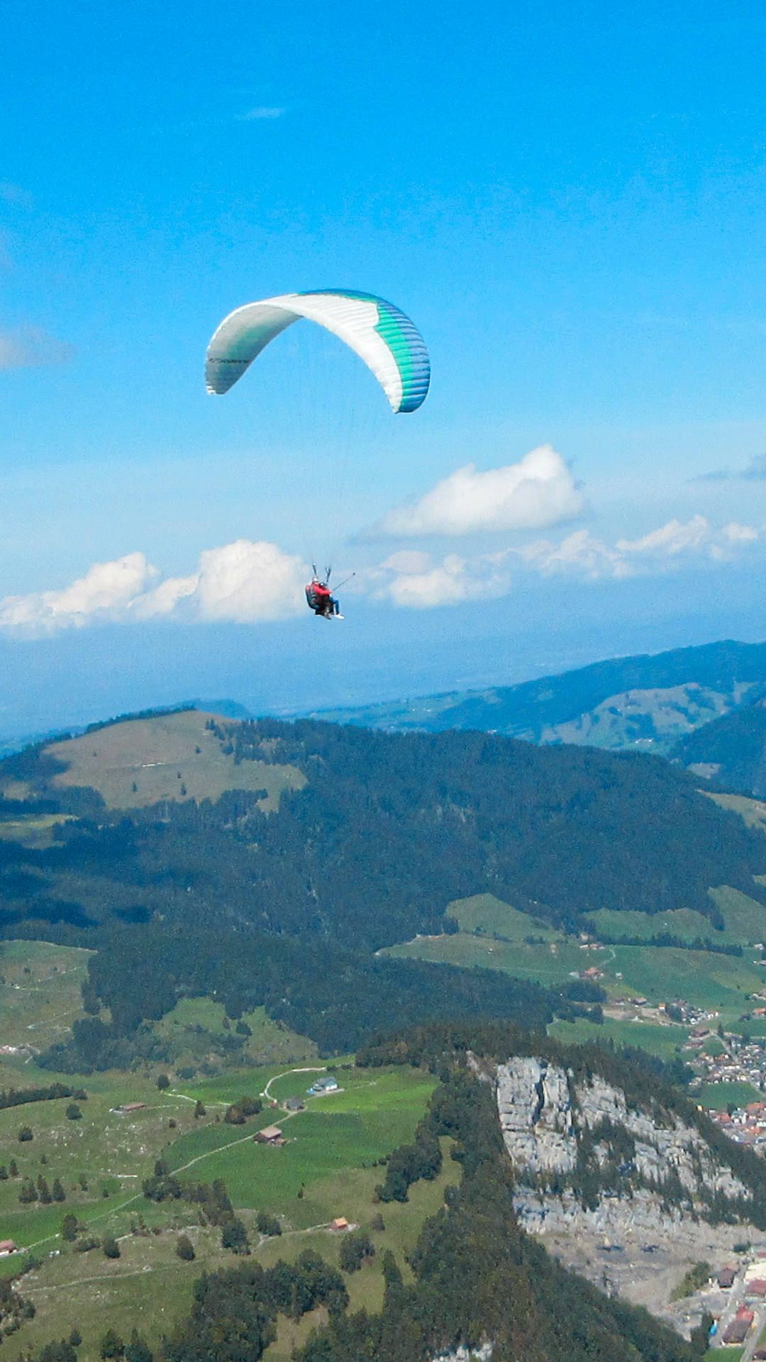 Flugaufnahme: Ein Tandemschirm dreht in der Thermik Kreise über Weglosen im Fluggebiet Hoch-Ybrig.