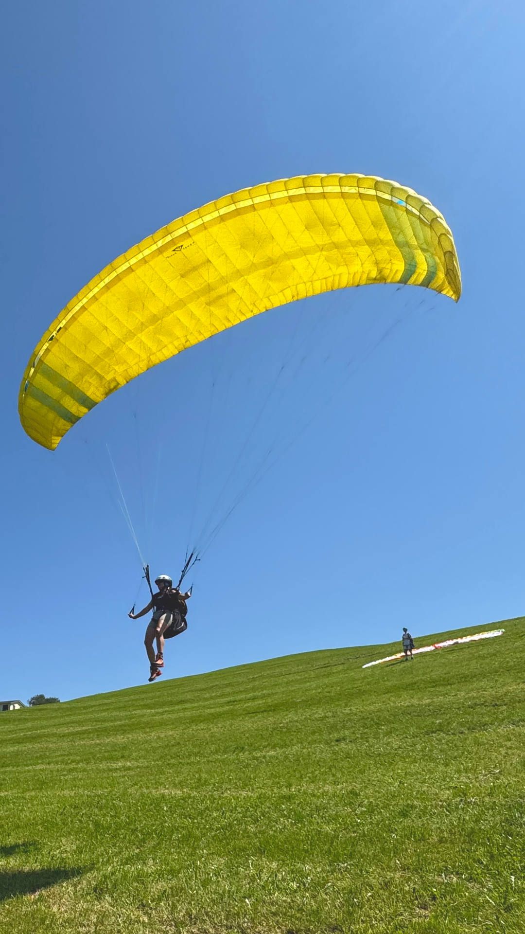 gleitschirm-uebungshang-flugschuelerin-abgehoben-hoch Eine Flugschülerin ist mit dem Schulgleitschirm abgehoben und segelt in voller Konzentration den Übungshang herunter.
