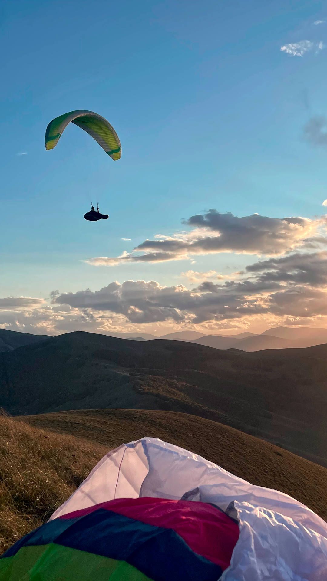 Kurz vor Sonnenuntergang geniesset ein Gleitschirmpilot im laminaren Aufwind die Abendstimmung in der Luft.