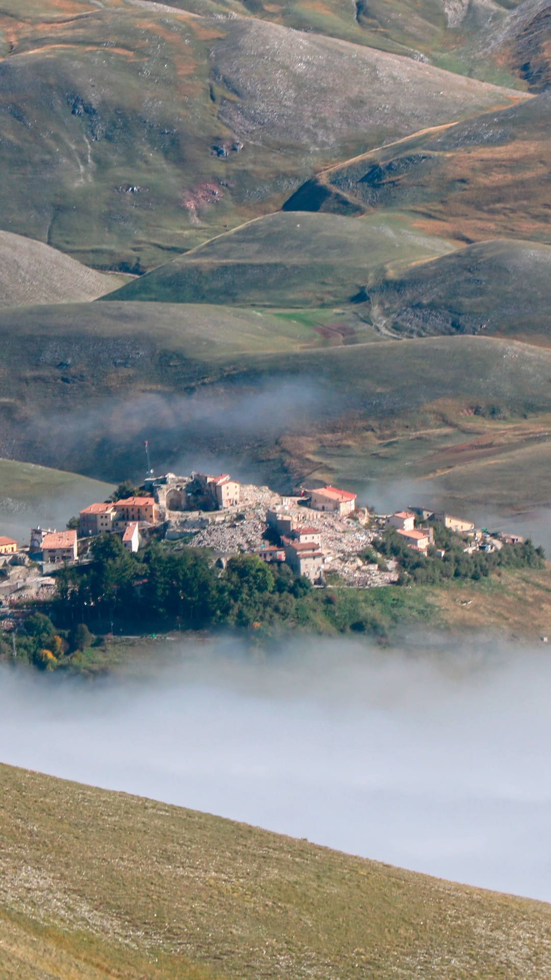 Die Auflösung des morgendlichen Nebels gibt den Blick auf das von Erdbebenschäden versehrte Castelluccio frei.