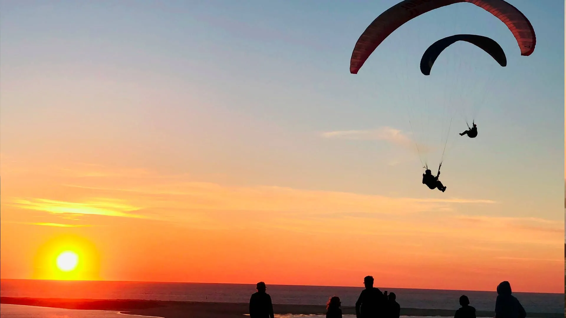 gleitschirmreise-duene-du-pyla-abendsoaring-sonnenuntergang-petit-nice-quer Zwei Gleitschirme nutzen die letzten Aufwinde des Tages und bieten den Zuschauern einen Tanz in der Luft.