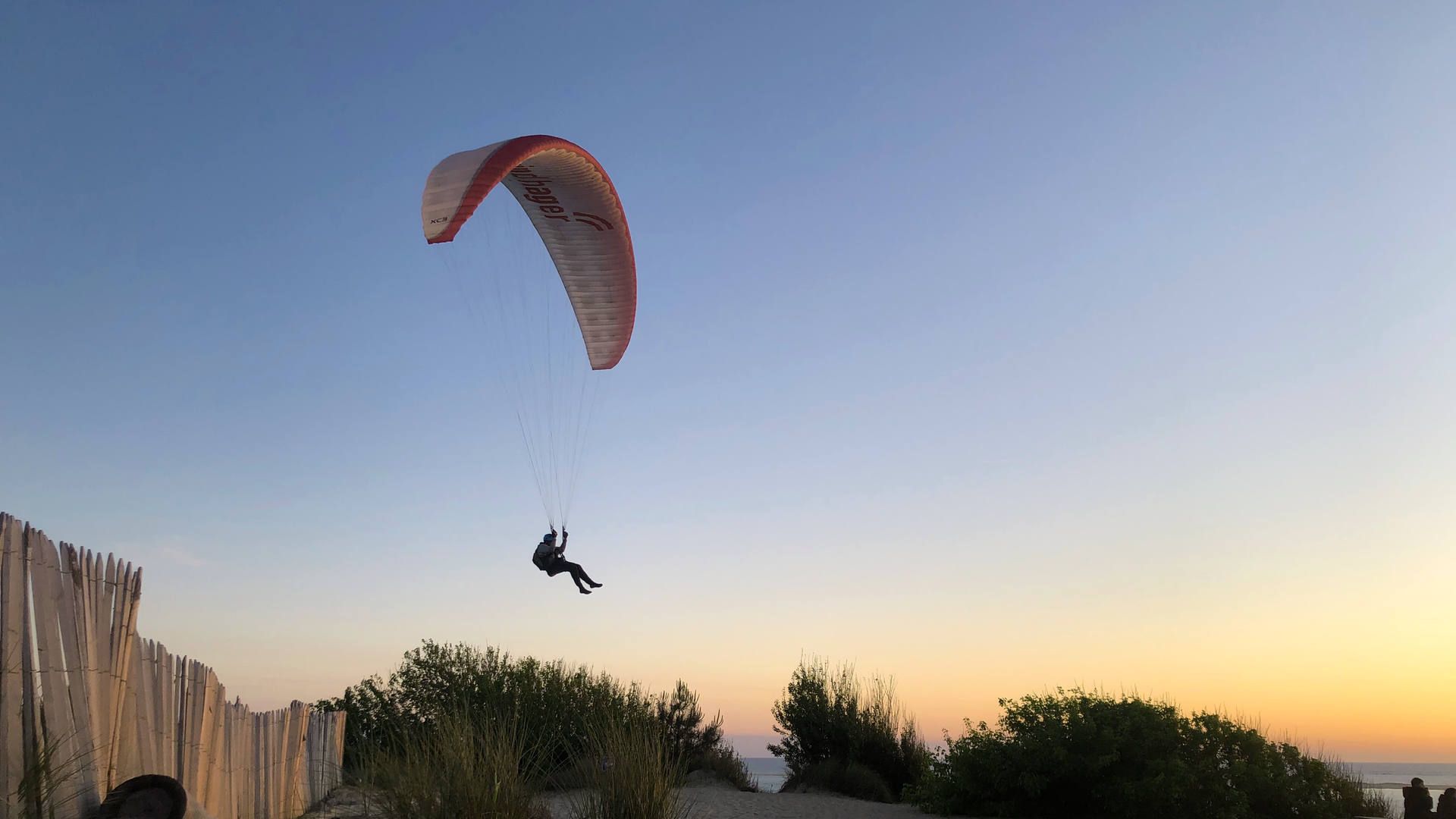 Ein Gleitschirmpilot setzt beim Startplatz Petit Nice zur Landung abn, bevor die Meeresbrise nach Sonnenuntergang abstellt.