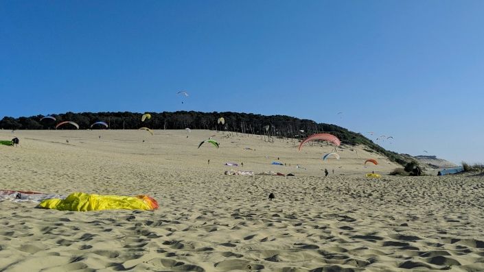 Impression von der Dune du Pyla Gleitschirmpiloten kiten die Düne hoch, andere fliegen im laminaren Aufwind oder ziehen einfach nur Schirm auf.