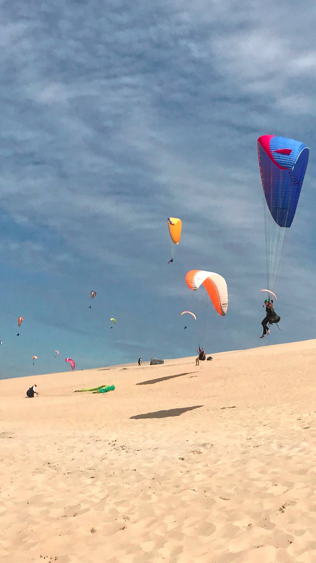 Lebhafte Szene an der Düne mit vielen fliegenden Gleitschirmen an der grossen Dune du Pyla.